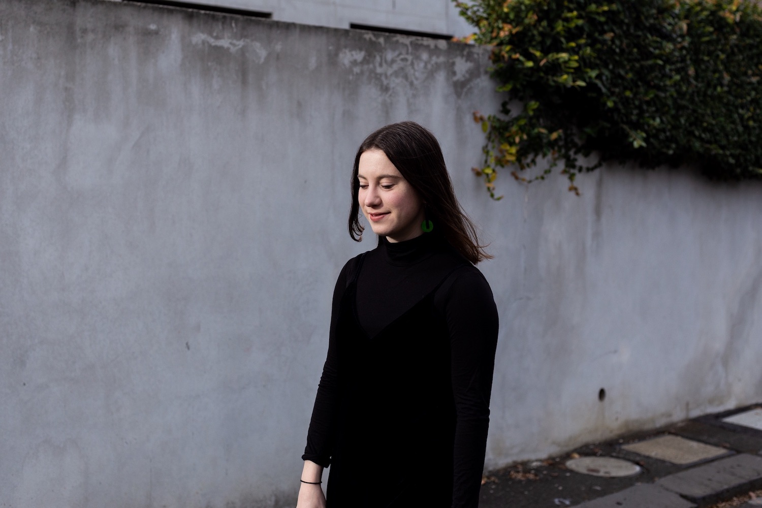 Imogen Cygler in front of a concrete wall with vines